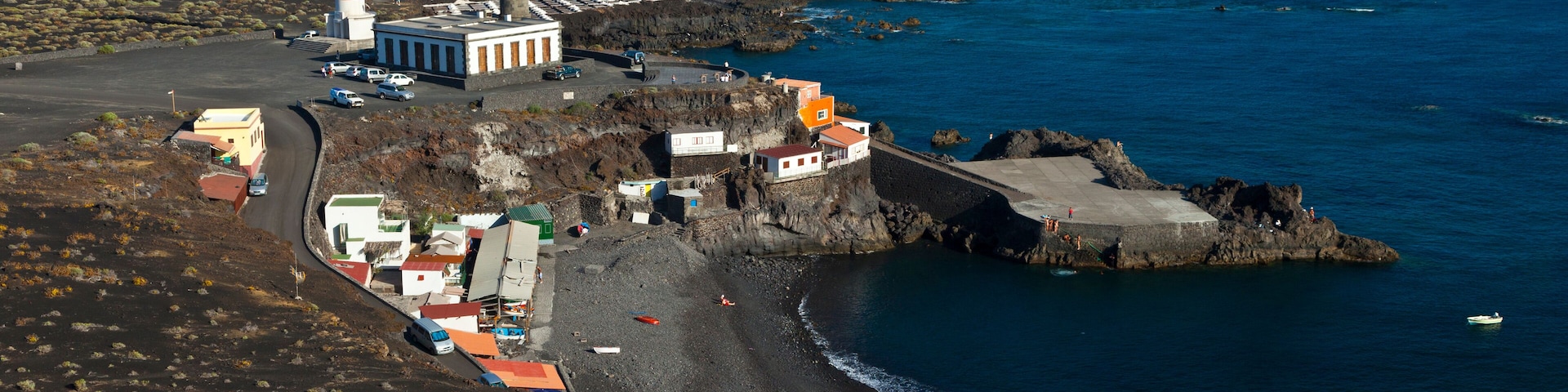 A coastal town with a lighthouse, rocky shoreline, and a beach.