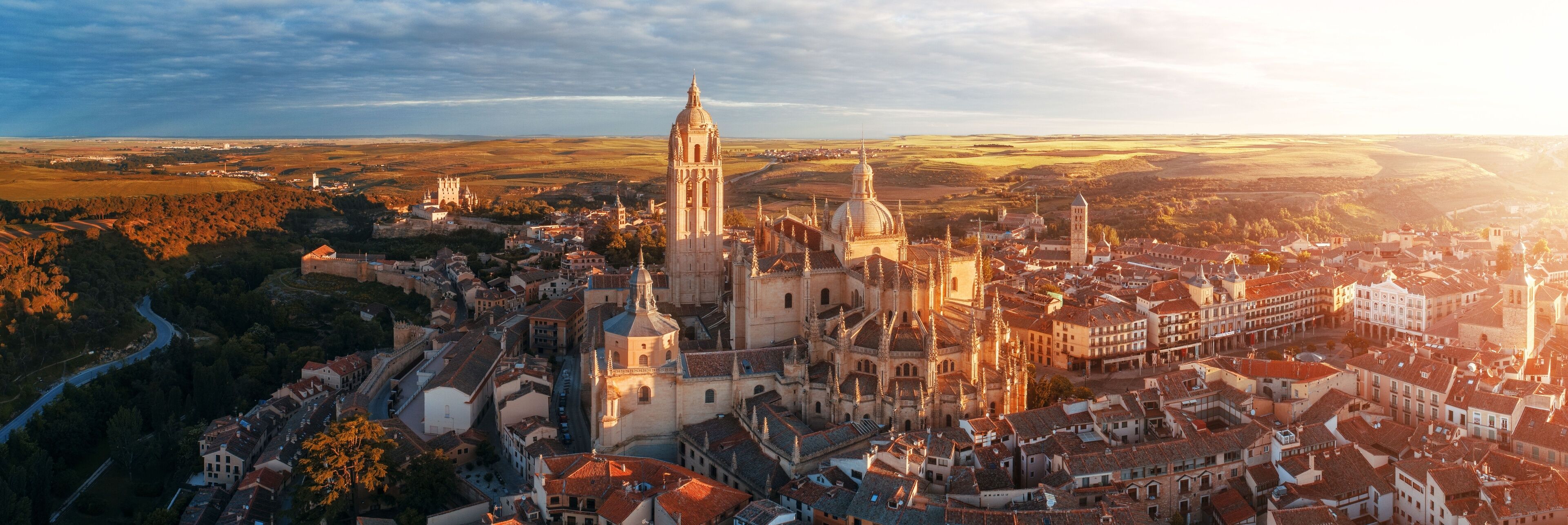 A historic cityscape with a prominent cathedral, surrounded by a river and rolling hills in the background.