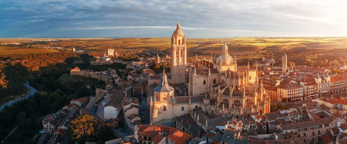 A historic cityscape with a prominent cathedral, surrounded by a river and rolling hills in the background.