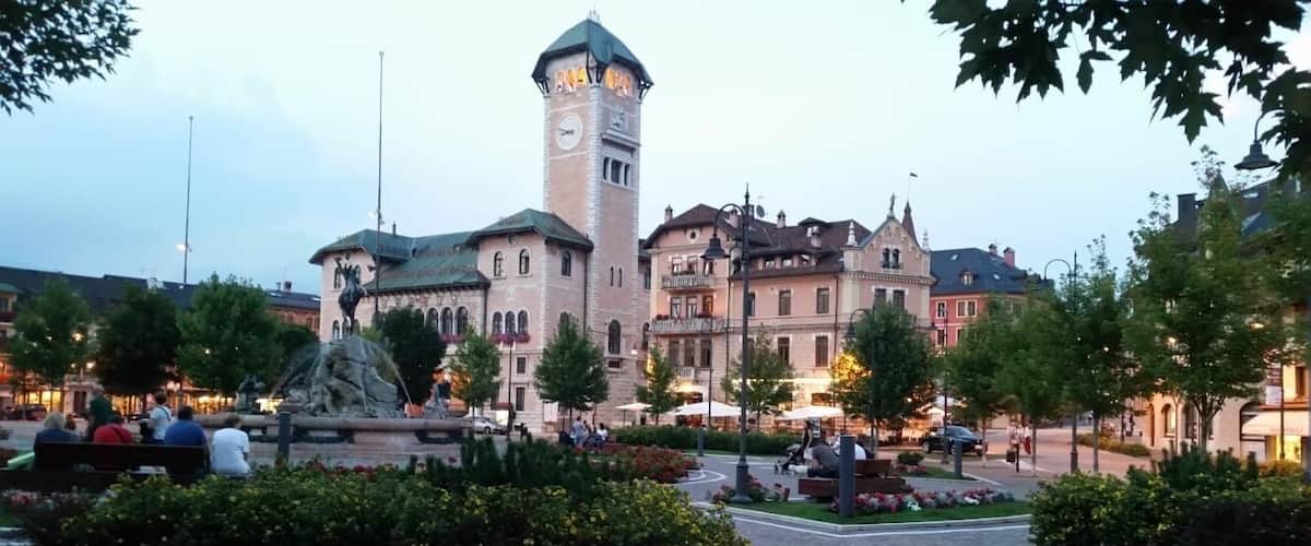 A historic town square with a prominent clock tower, cobblestone streets, and surrounding buildings.