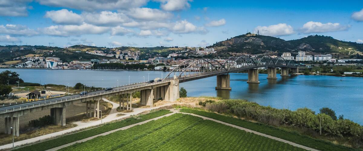 A bridge over a river with a cityscape in the background.