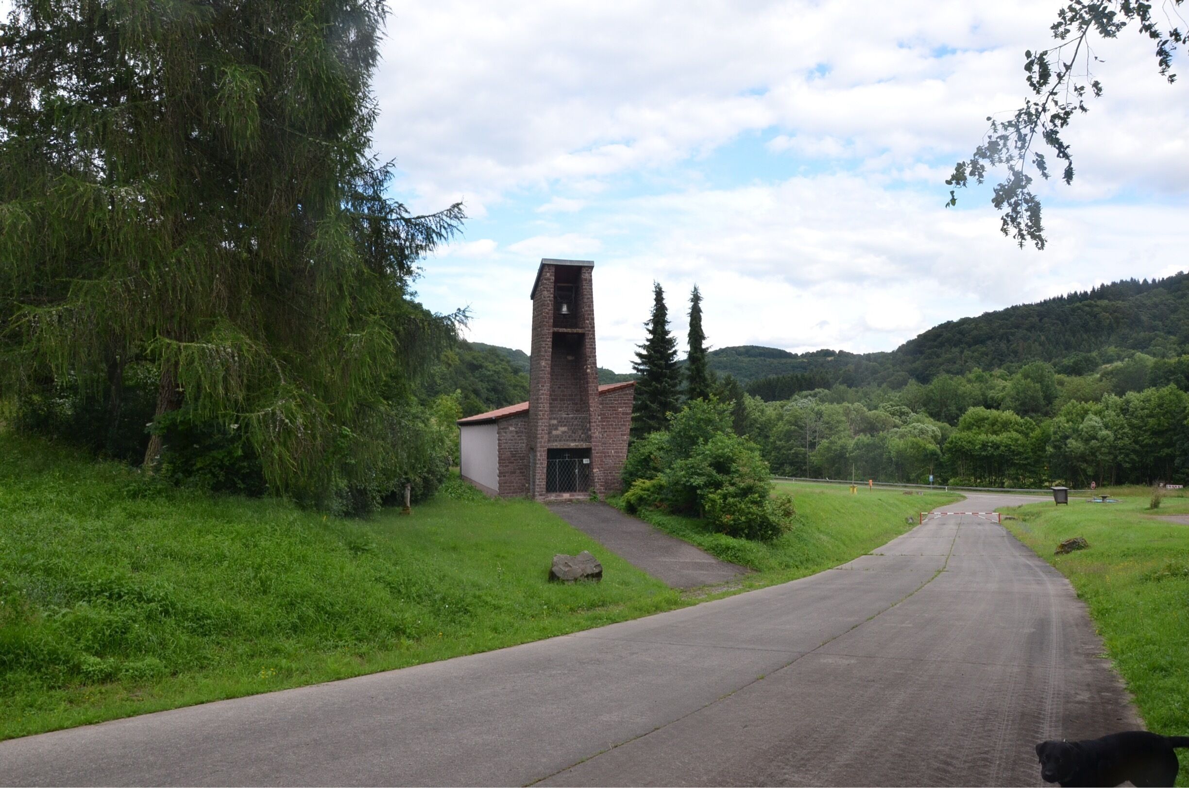 A rural road with a brick building and a dog.