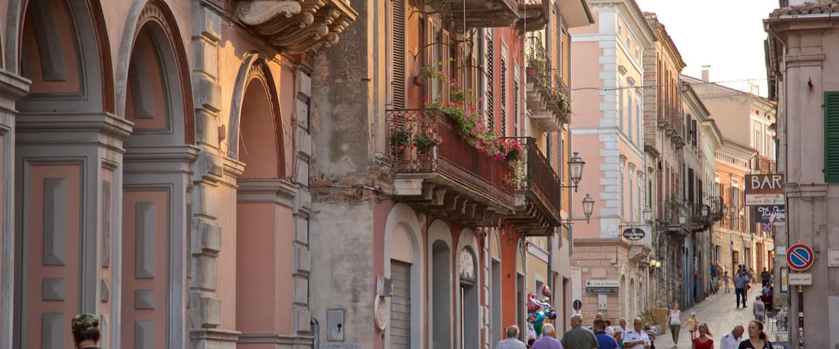 A cobblestone street lined with historic buildings, a bar sign, and pedestrians.