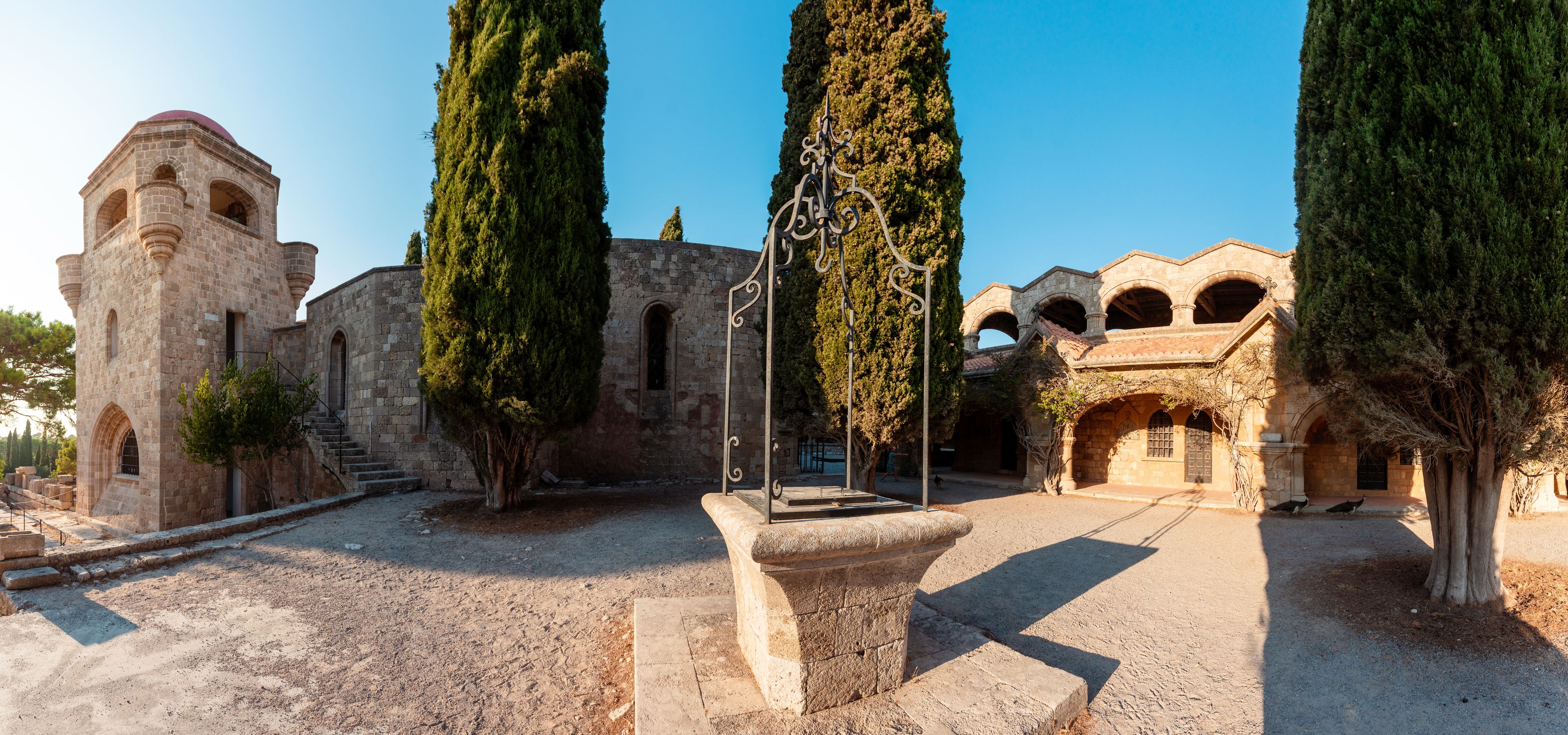 An ancient stone building with arched windows and a tower.