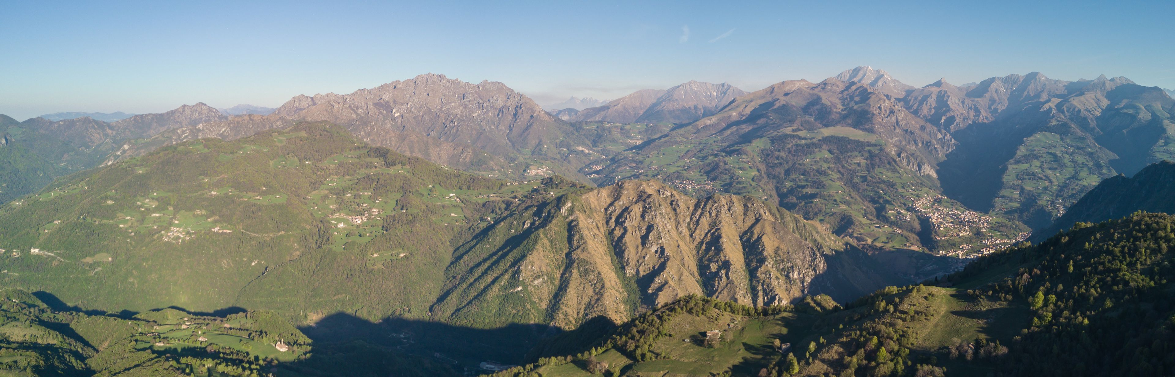 Drone aerial view to the Seriana valley and Orobie Alps in a clear and blue day. View of the highest mountains including Arera. Panorama from Farno Mountain, Bergamo, Italy. 