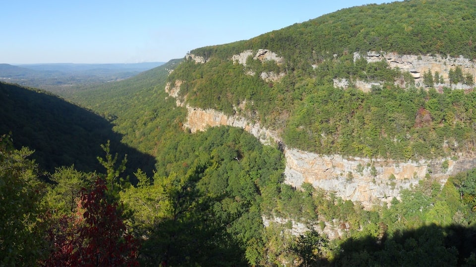 A mountainous landscape with dense forests and rocky cliffs.