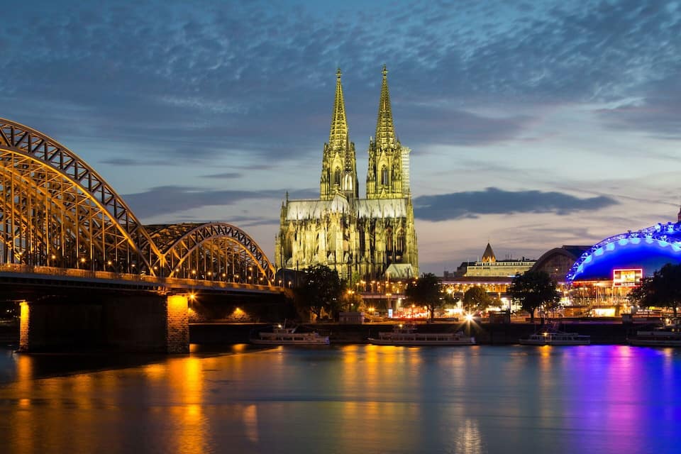 Un pont, une cathédrale et une grande roue au crépuscule.