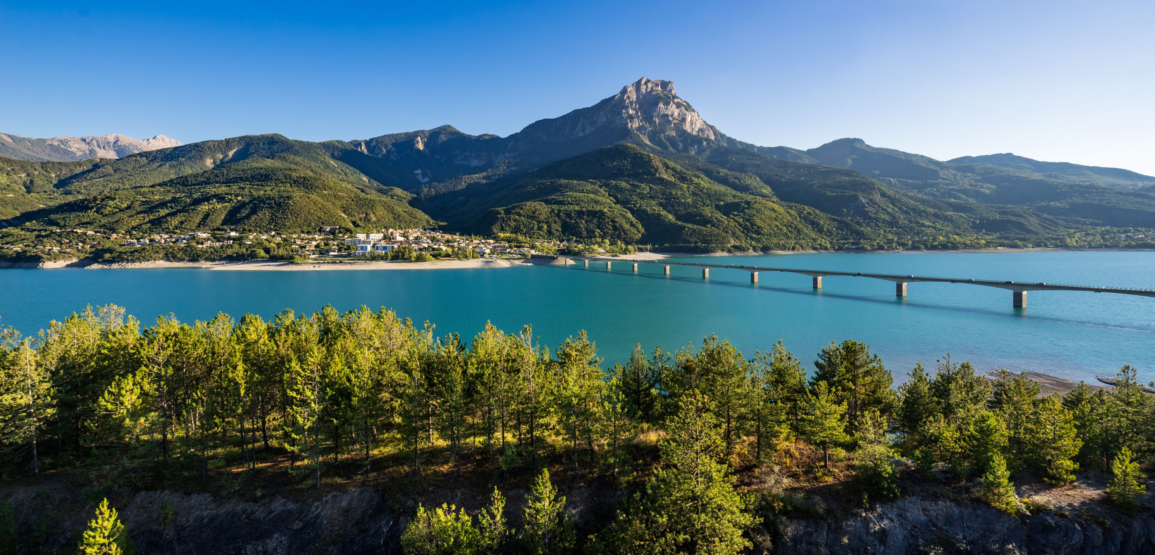 Summer panoramic view of Serre-Poncon Lake with Savines-le-Lac, its bridge and the Grand Morgon mountain peak. Hautes-Alpes, PACA Region, Southern French Alps, France