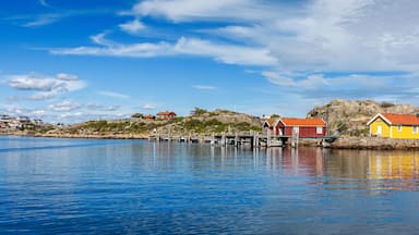 A coastal village with colorful houses, a pier, and rocky hills.