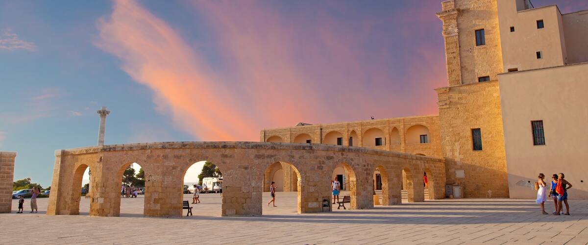 An ancient stone archway with a tower, set against a backdrop of a pink and blue sky.