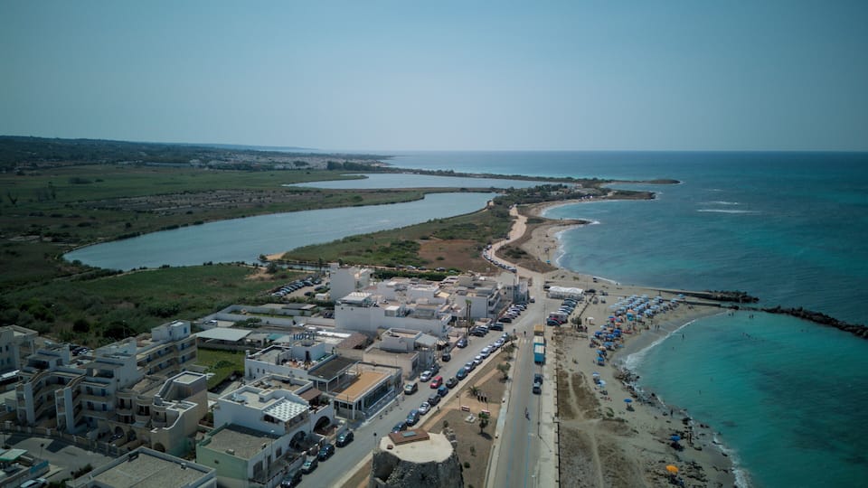 A coastal town with a beach, a marina, and a road leading to the beach.