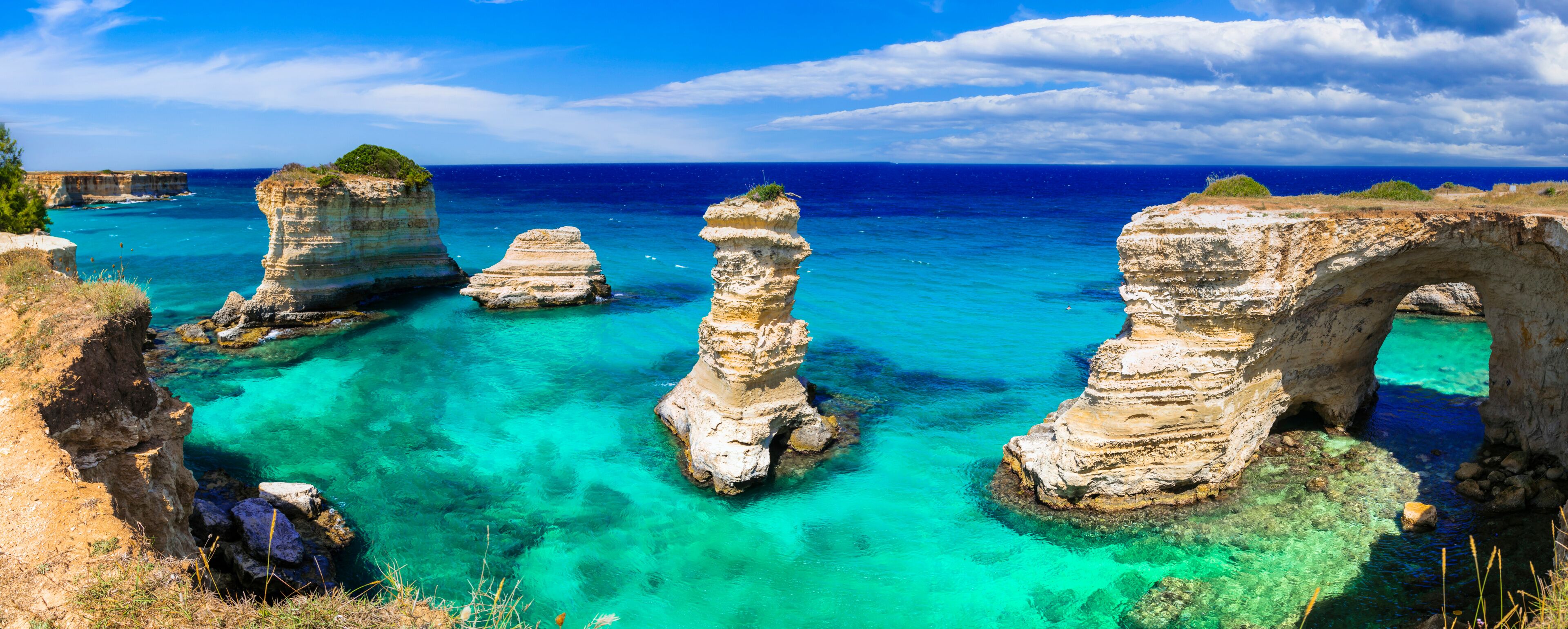 A coastal landscape with clear turquoise waters and rock formations.
