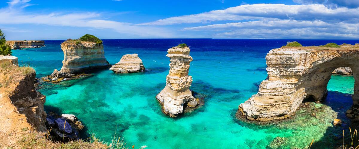 A coastal landscape with clear turquoise waters and rock formations.