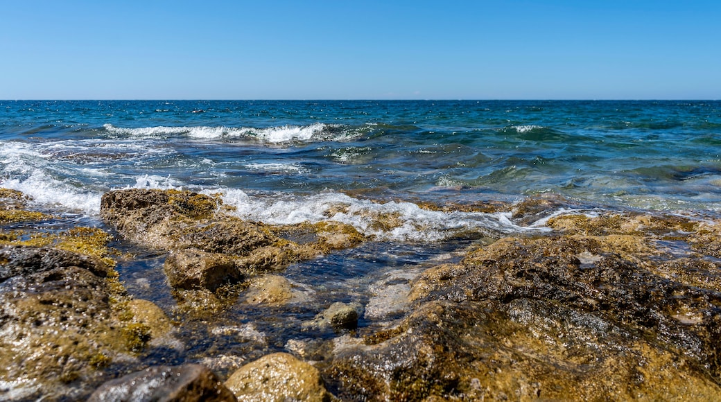 Rocky shore of Posto Rosso, Salento, Puglia, Southern Italy, in a sunny summer day, with bright colors, clear water and blue sky.