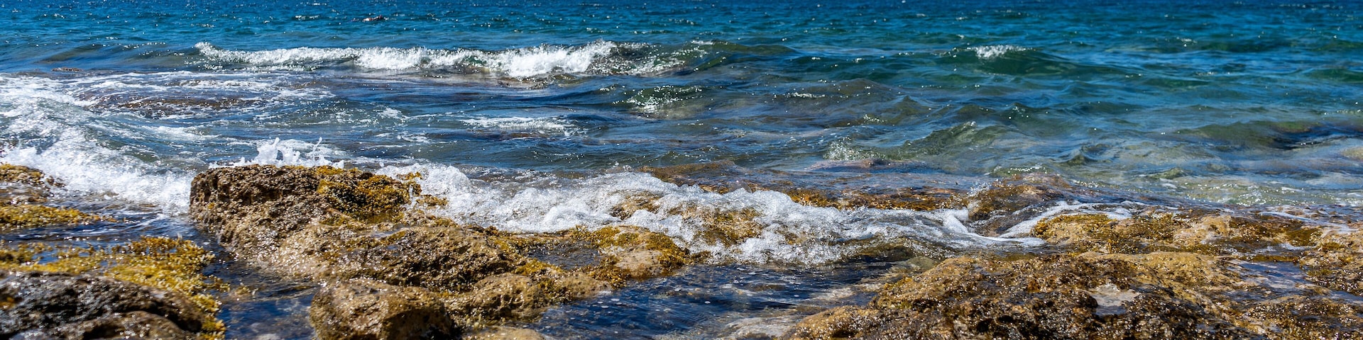 Rocky shore of Posto Rosso, Salento, Puglia, Southern Italy, in a sunny summer day, with bright colors, clear water and blue sky.
