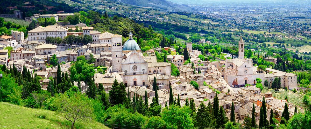 A historic town with a prominent church, lush greenery, and rolling hills in the background.