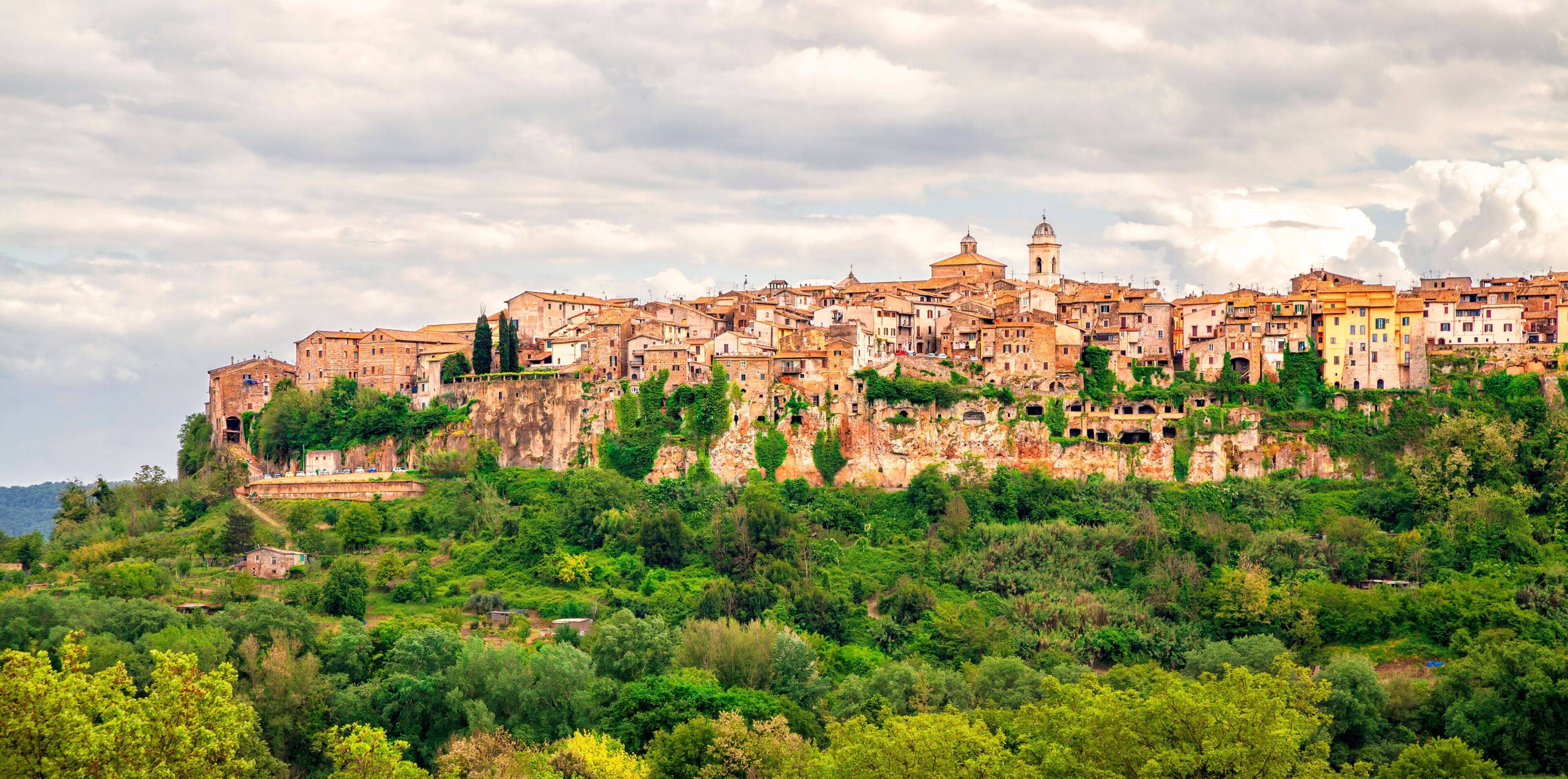 A historic town built on a hillside with ancient buildings and lush greenery.