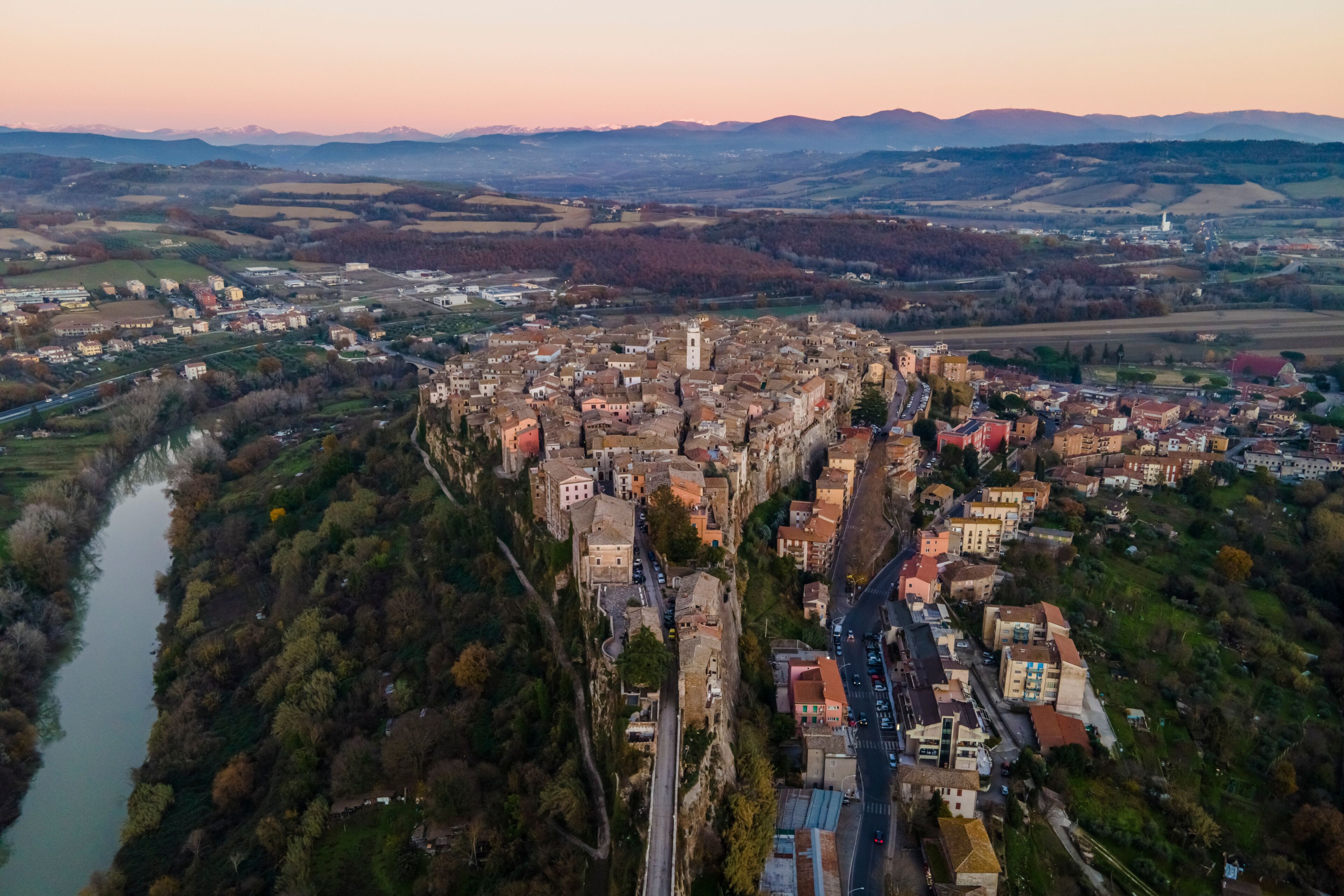 Vista aérea de un pueblo histórico con un río, edificios densos y colinas circundantes.