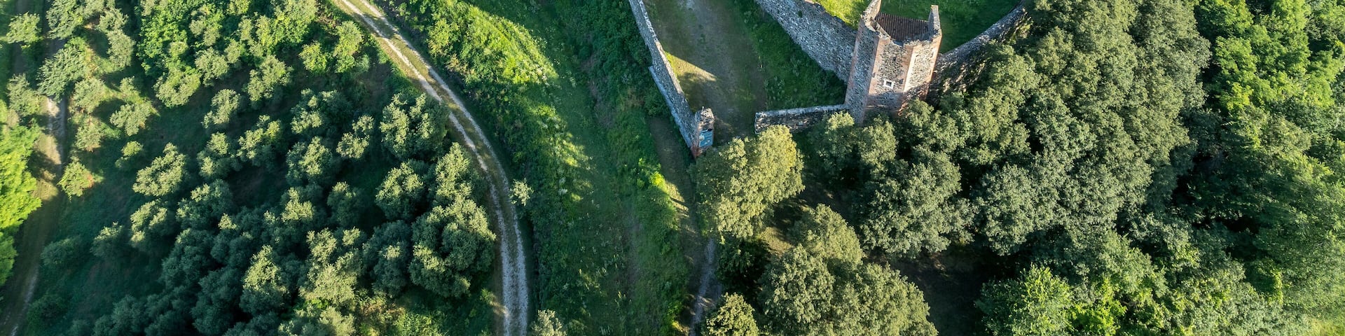 An aerial view of a historic castle surrounded by lush greenery and agricultural fields.