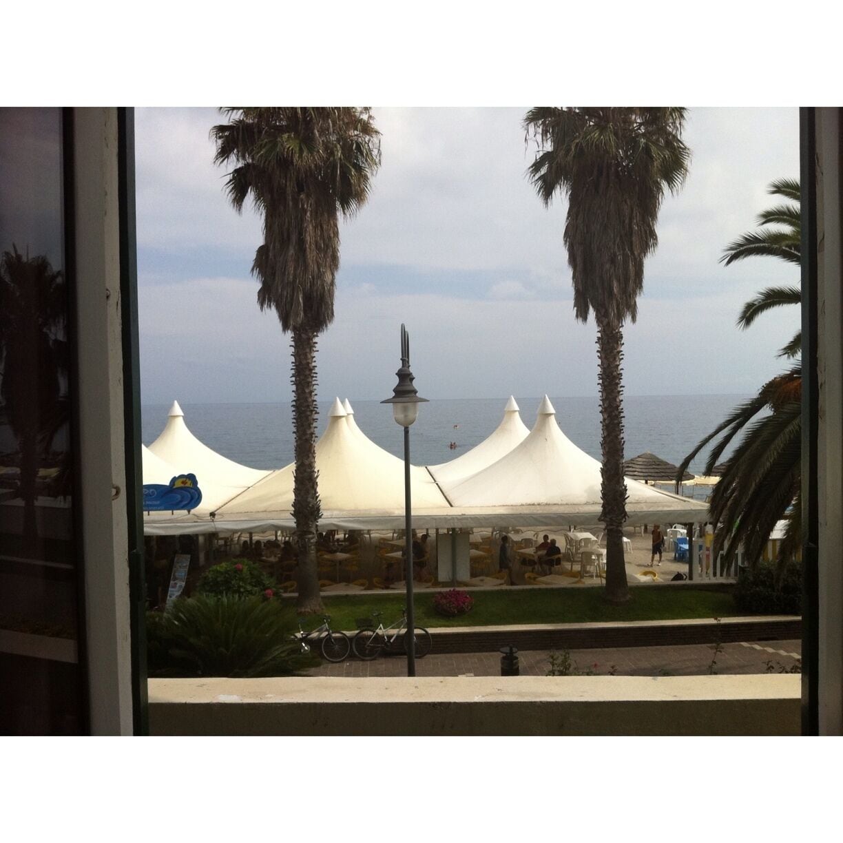 A view of a beach with white tents and palm trees.