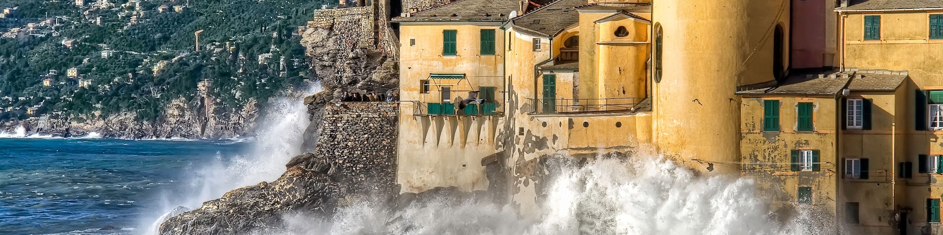 A coastal town with historic buildings, a church, and waves crashing against the shore.