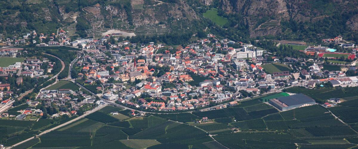 A mountainous town with terraced vineyards, a church, and a mix of residential and commercial buildings.
