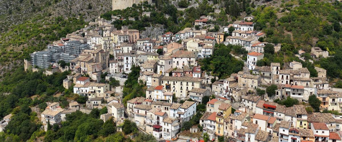 A hillside village with historic stone buildings and a castle.