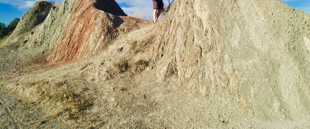 A person standing on a large pile of earth with a clear blue sky in the background.