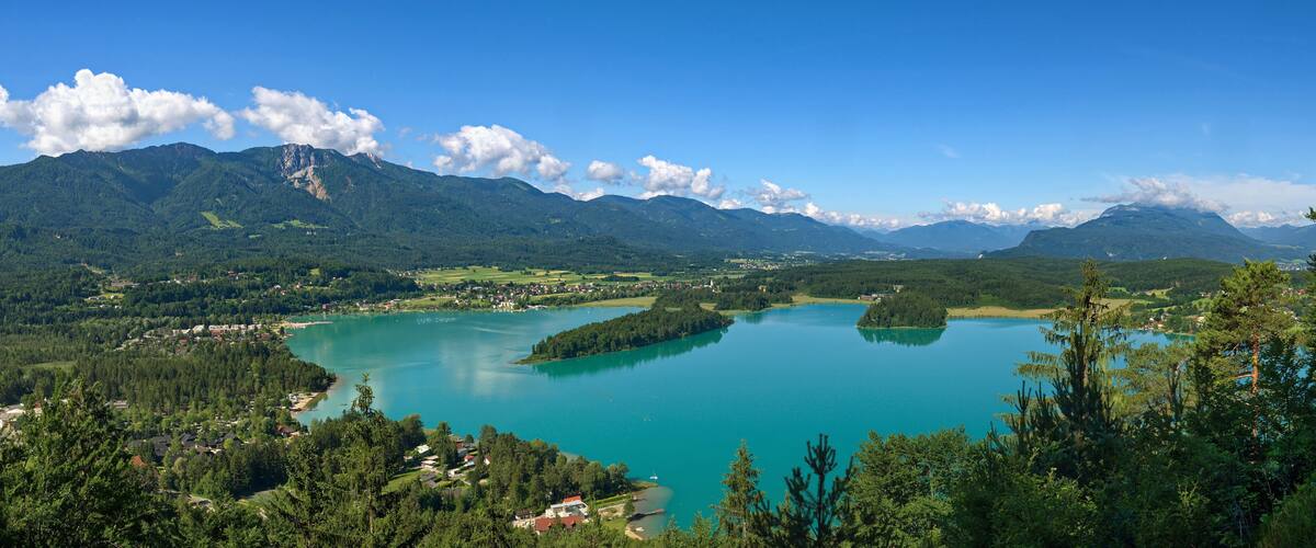 A lake surrounded by mountains, a small town, and dense forest.