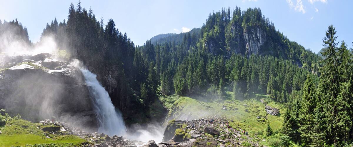 A waterfall cascading down a rocky cliff surrounded by dense forest.