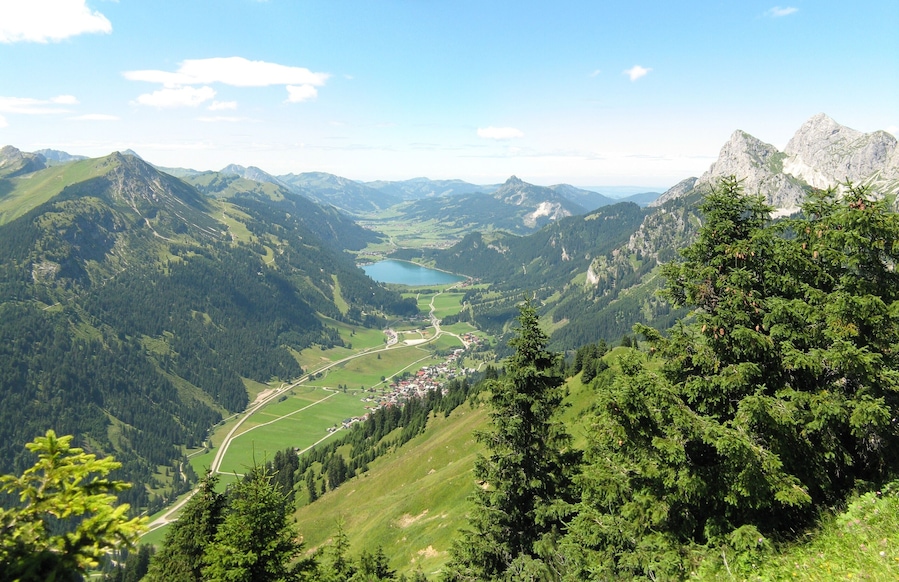 Eine Berglandschaft mit einem See, bewaldeten Gebieten und einem kleinen Dorf.