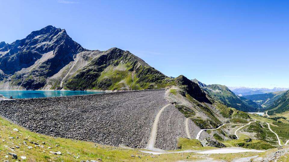 A mountain landscape with a reservoir, roads, and a small settlement.