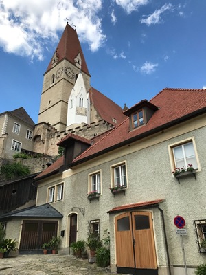 Ein historisches Gebäude mit einem Glockenturm, einem roten Ziegeldach und Blumenkästen.