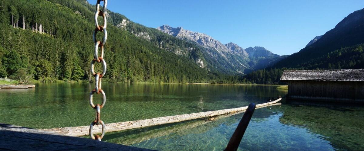 A clear mountain lake with a wooden dock and a small boat.
