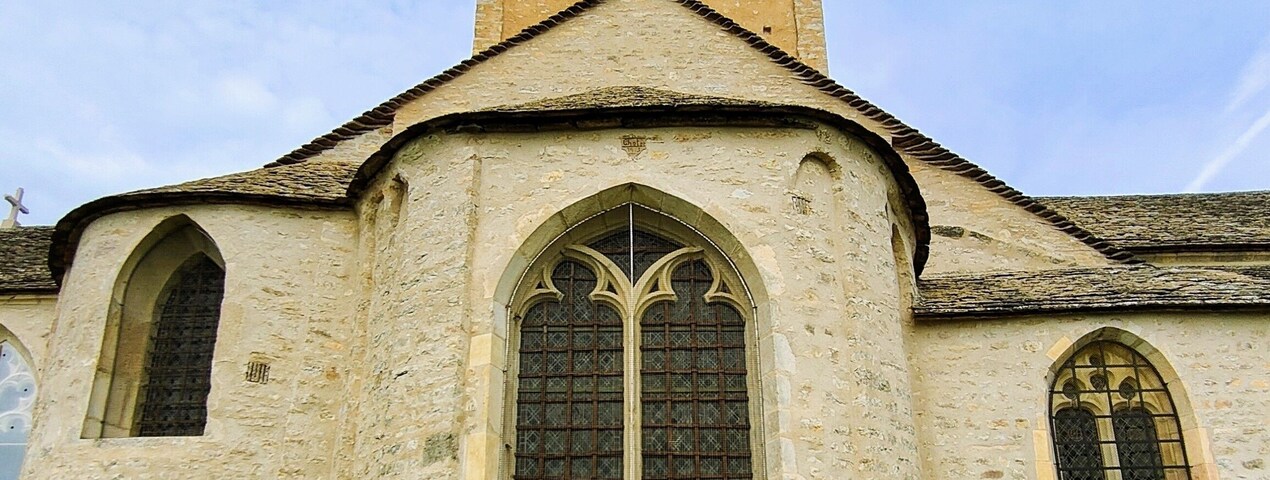 Una iglesia histórica con una torre de campanas, ventanas de arco y fachada de piedra.