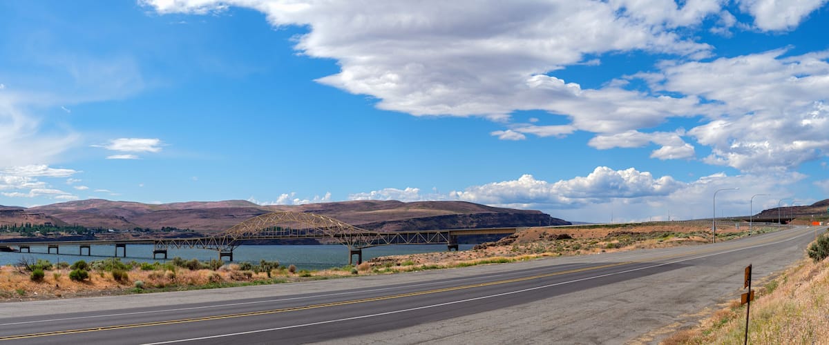A bridge over a river with mountains in the background.