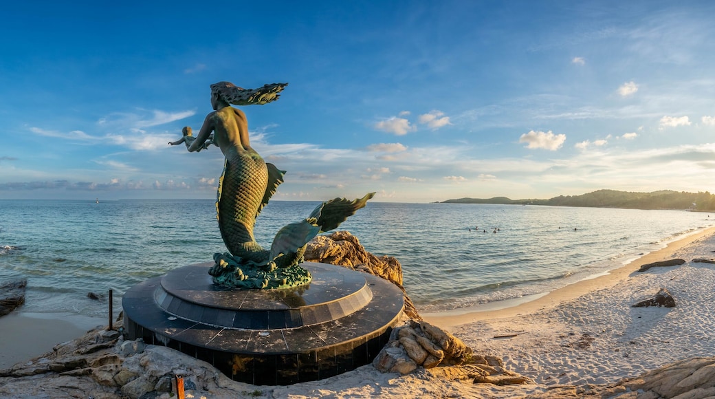 Mermaid sculpture in outdoor public sand and rock beach with seascape view at Samet island, Rayong, Thailand, under twilight sunset cloudy sky