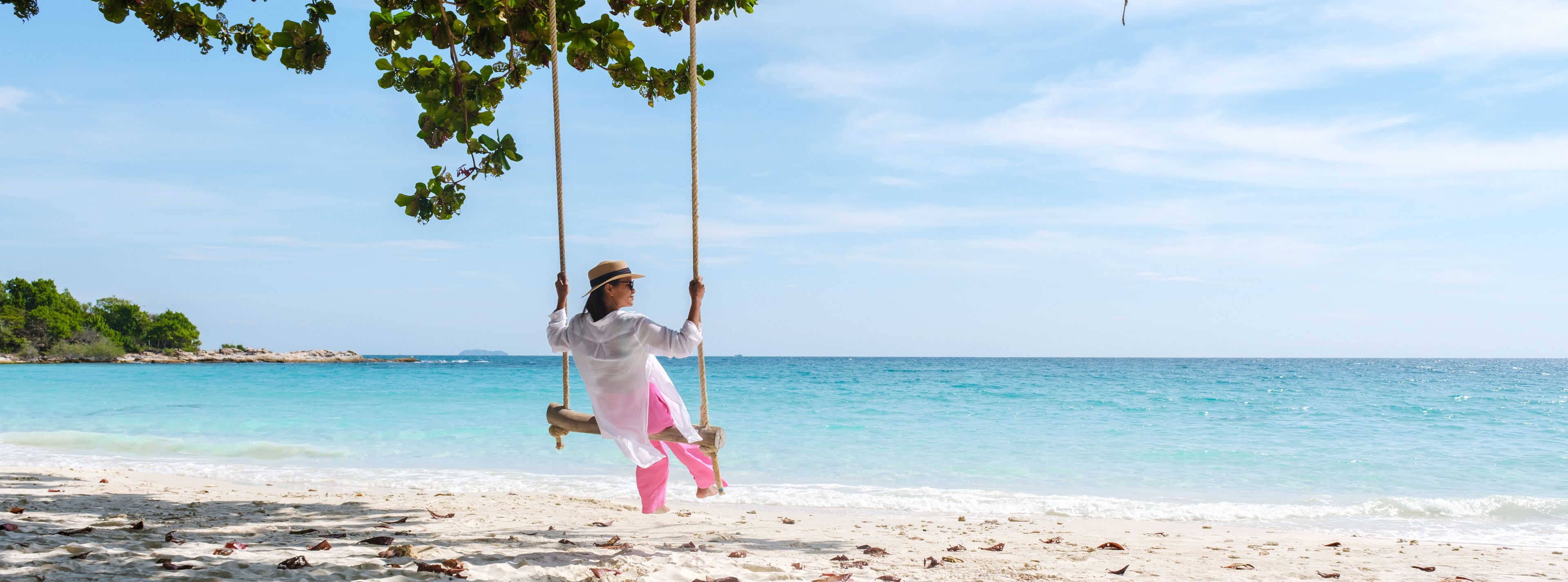 Asian woman on a swing at the beach of Koh Samet Island Rayong Thailand, the white tropical beach of Samed Island with a turqouse colored ocean on a sunny afternoon