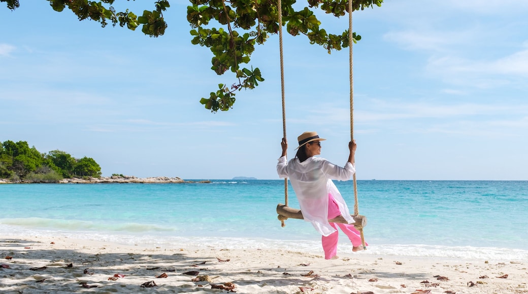 Asian woman on a swing at the beach of Koh Samet Island Rayong Thailand, the white tropical beach of Samed Island with a turqouse colored ocean on a sunny afternoon