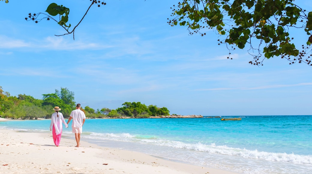 A couple of men and woman walking on the beach of Koh Samet Island Thailand, the white tropical beach of Samed Island with a turqouse colored ocean, Asian Thai woman and European men on the beach