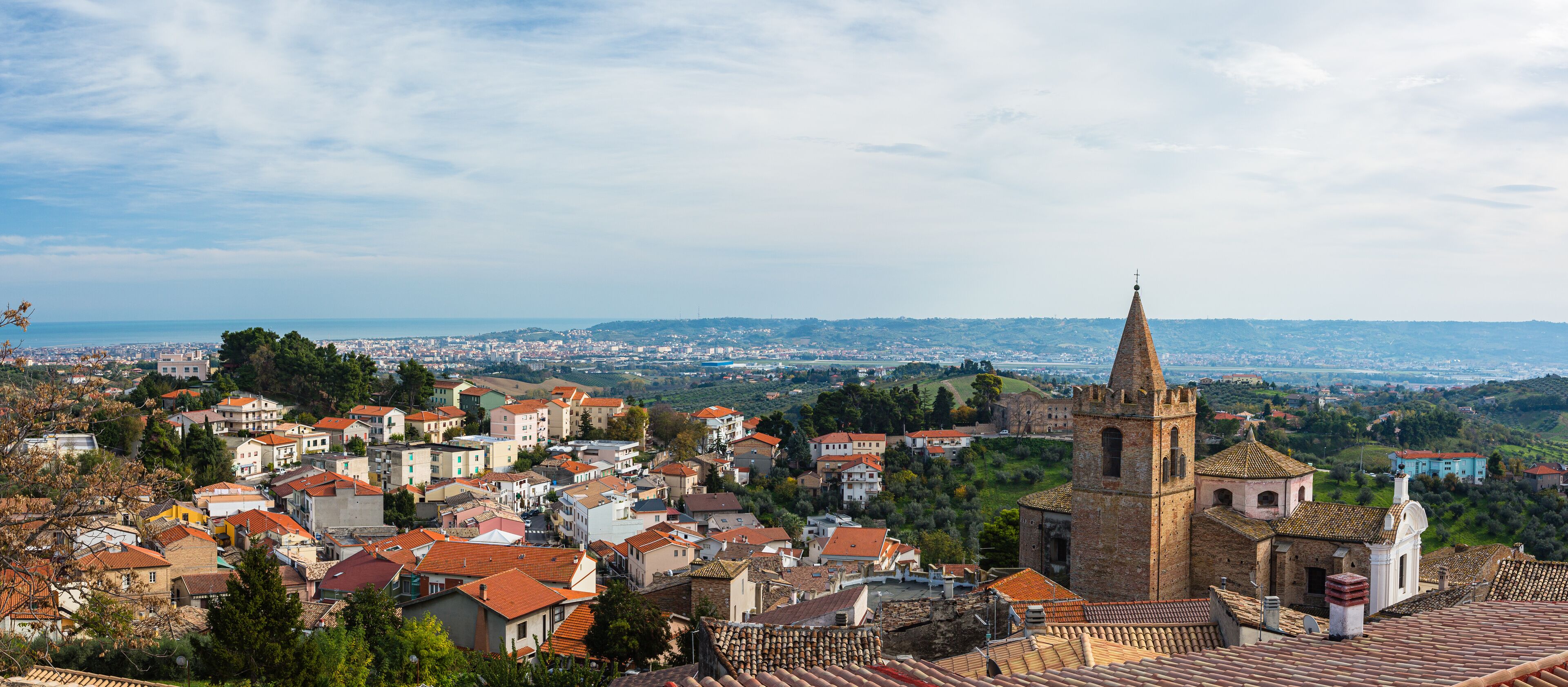 A town with a prominent church tower and a view of the cityscape in the background.