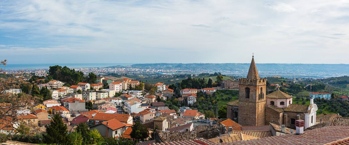 A town with a prominent church tower and a view of the cityscape in the background.