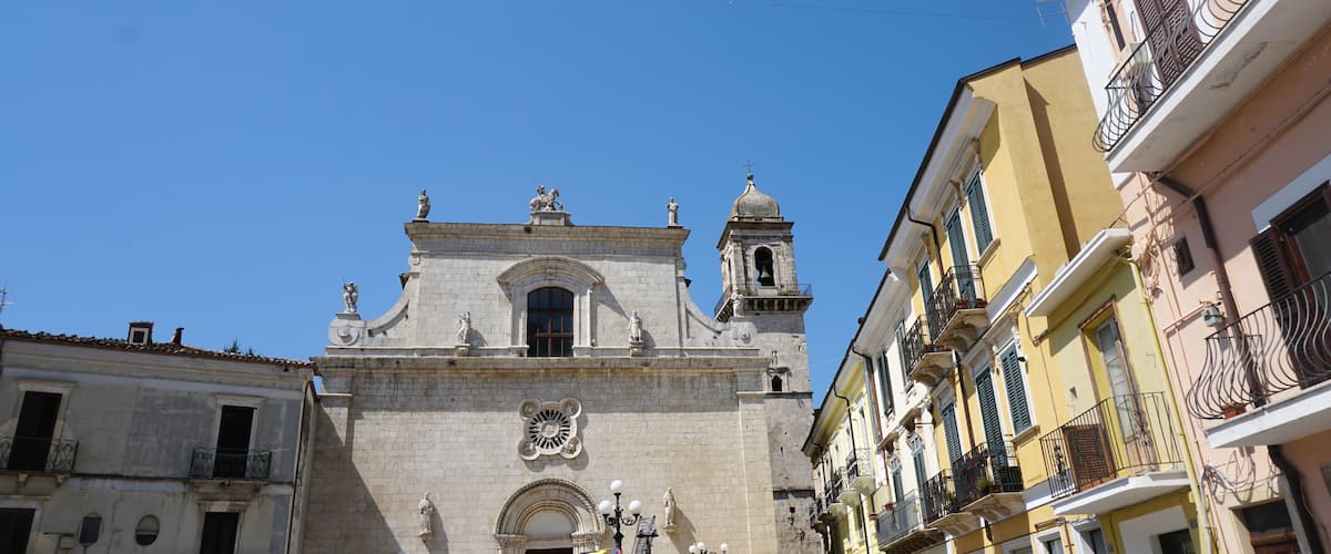 A historic church with a bell tower and statues on its facade.