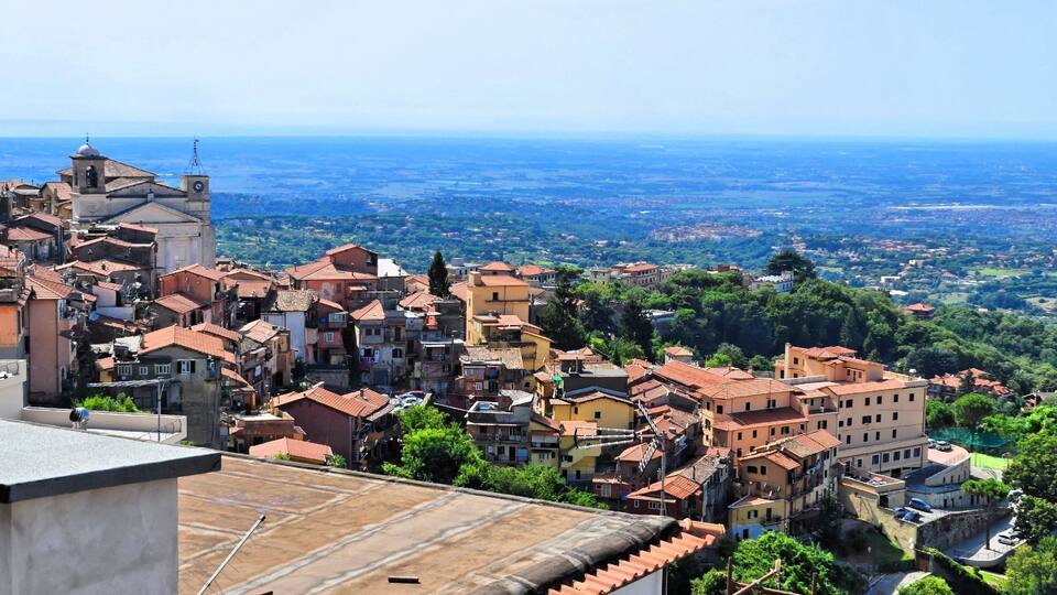 A densely packed town with red-tiled roofs and a prominent church tower.