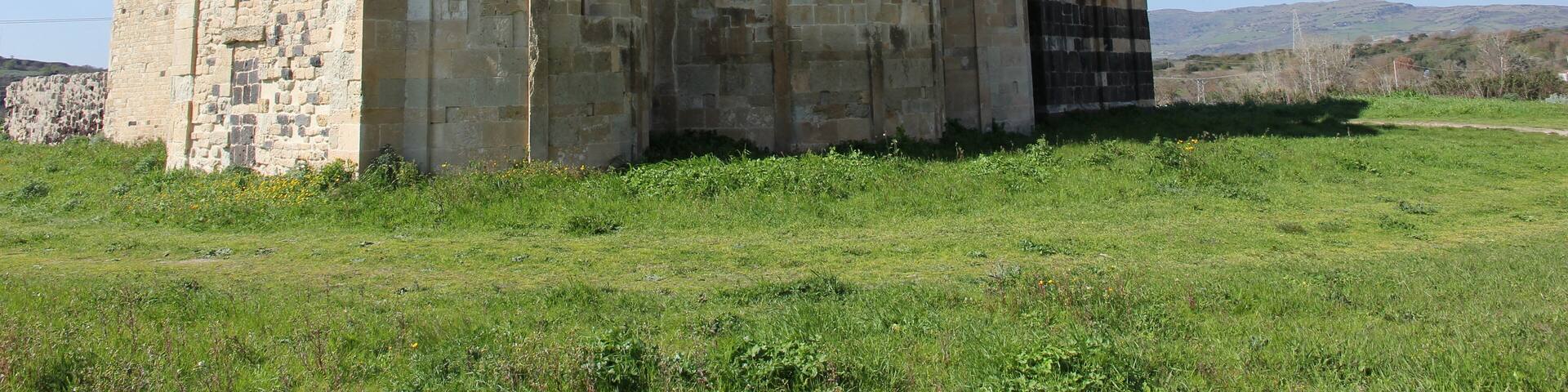 An ancient stone building with arched windows and a bell tower.