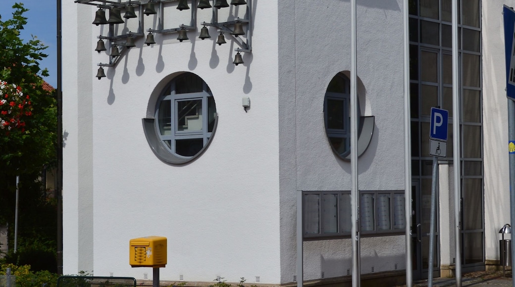 Un bâtiment moderne doté d’une tour horlogée, d’une girouette et d’un panneau indiquant un parking.