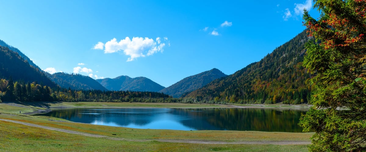 A serene lake surrounded by mountains and autumn foliage.