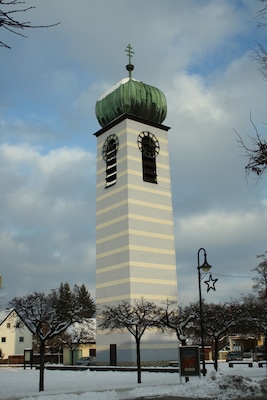 Ein hoher Turm mit einer grünen Kuppel und gestreiften Wänden.