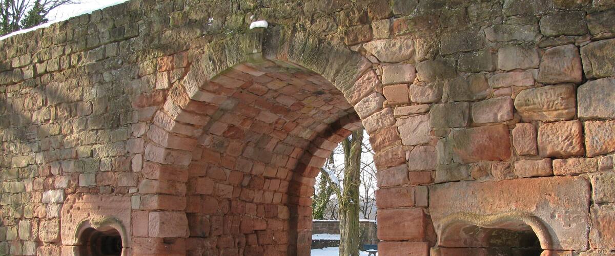 Das AuĂentor der Burg Nanstein in Rheinland Pfalz. Es befindet sich zu FĂŒĂen des Kleinen Rondells am sĂŒdlichen Ende der Burg. Der Torbau ist 4 Meter stark und wurde im oberen Bereich teilweise rekonstruiert. Die beiden Brillenscharten sind original: Sie dienten dem Einsatz von Handfeuerwaffen. Der Torbau entstand im spĂ€ten 16. Jahrhundert.