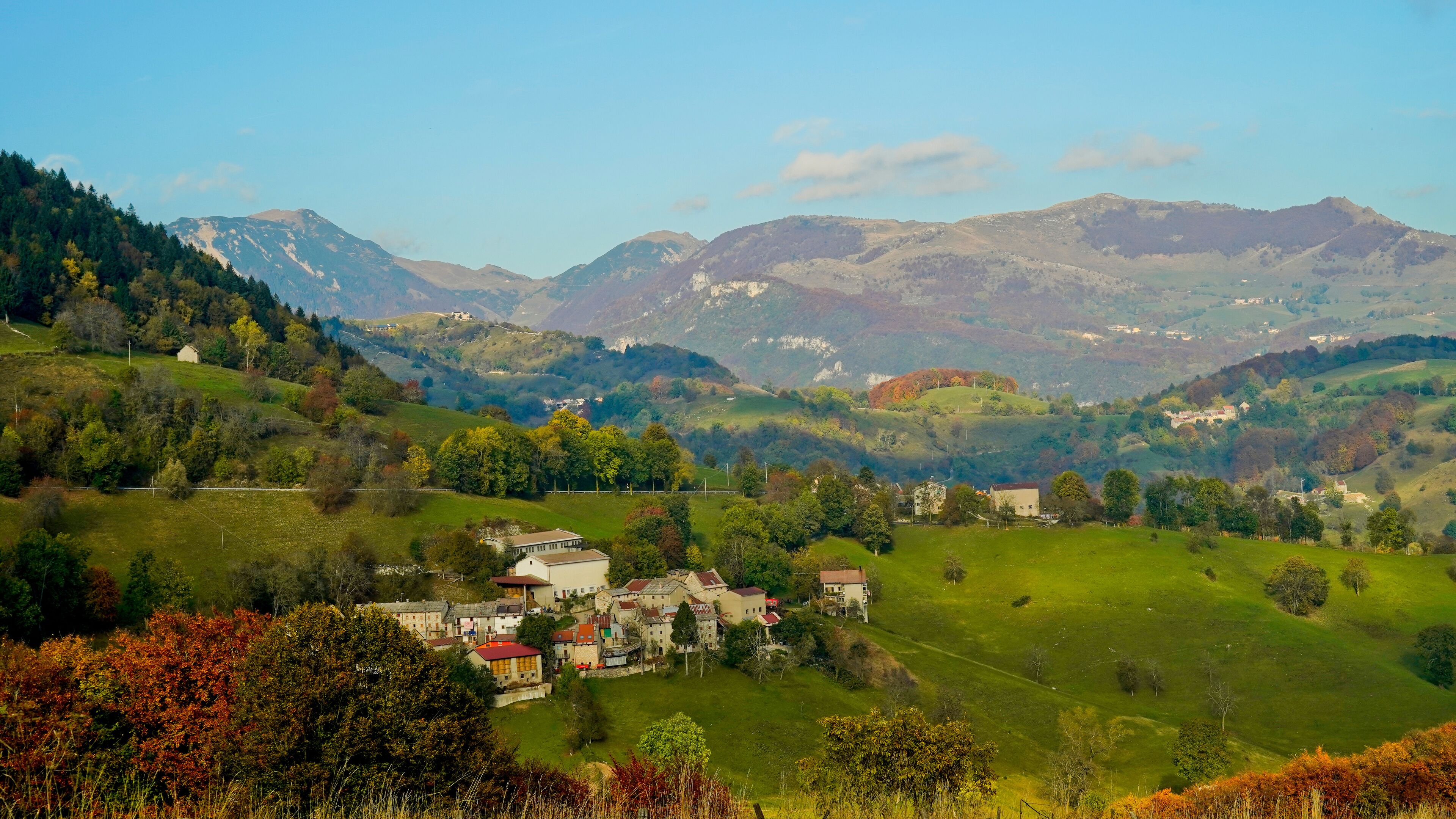 A valley with houses and mountains in the background.